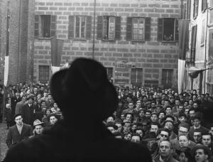 Scena del film "Il cappotto" - Regia Alberto Lattuada - 1952 - L'attore Giulio Stival, di spalle, su un palco parla a una folla di ascoltatori