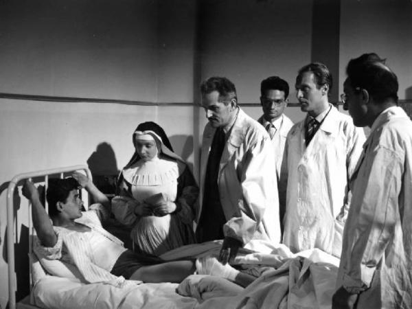 Scena del film "Anna" - Regia Alberto Lattuada - 1951 - Gli attori Jacques Dumesnil e Piero Lulli in camice bianco osservano un paziente assieme a medici e infermieri in ospedale