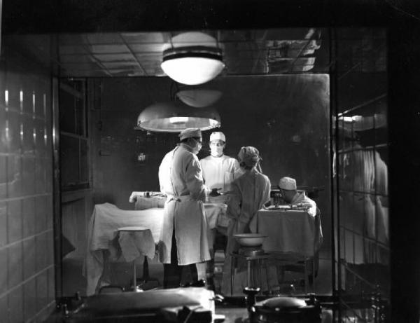 Scena del film "Anna" - Regia Alberto Lattuada - 1951 - Gli attori Jacques Dumesnil e Piero Lulli, in camice bianco in sala operatoria con attori non identificati