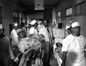Scena del film "Anna" - Regia Alberto Lattuada - 1951 - Gli attori Jacques Dumesnil in camice bianco in una corsia dell'ospedale con l'infermiere Mimmo Poli e altri non identificati che trasportano pazienti in barella