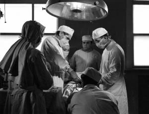 Scena del film "Anna" - Regia Alberto Lattuada - 1951 - Gli attori, Silvana Mangano, in veste di suora infermiera, Jacques Dumesnil, Piero Lulli, in camice bianco in sala operatoria con l'infermiere Mimmo Poli e altri attori non identificati