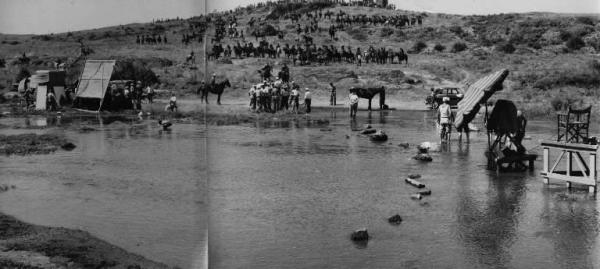 Set del film "Attila" - Regia Pietro Francisci - 1954 - Operatori della troupe ai bordi di un fiume per riprendere una scena con attori a cavallo su una collina