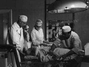 Scena del film "Anna" - Regia Alberto Lattuada - 1951 - Gli attori Jacques Dumesnil, in canottiera, Mimmo Poli e due infermieri assiston una pazienze stasa sul lettino