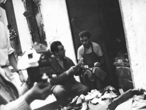 Set del film "La battaglia di Algeri" - Regia Gillo Pontecorvo - 1966 - Un operatore da indicazioni a un ciabattino