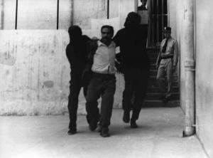 Scena del film "La battaglia di Algeri" - Regia Gillo Pontecorvo - 1966 - Un attore non identificato viene trascinato a forza da due uomini dal volto coperto