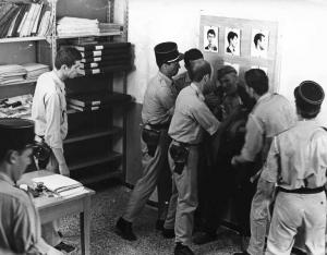 Scena del film "La battaglia di Algeri" - Regia Gillo Pontecorvo - 1966 - Agenti di polizia attorno a un attore non identificato