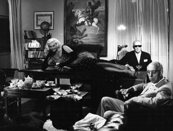 Scena dell'episodio "Le tentazioni del dottor Antonio" del film "Boccaccio '70" - Regia Federico Fellini - 1962 - L'attrice Anita Ekberg sdraiata su un tavolo e due attori non identificati