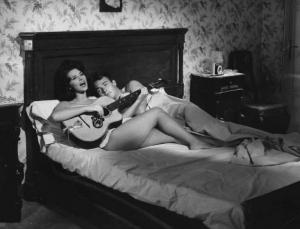 Scena del film "Carmen di Trastevere" - Regia Carmine Gallone - 1962 - Gli attori Giovanna Ralli, con una chitarra,e Jacques Charrier a letto