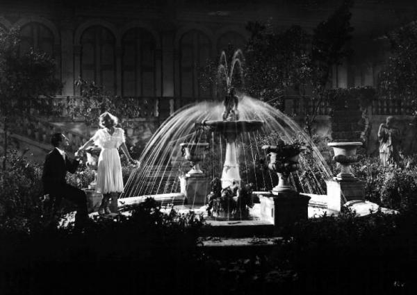 Scena del film "Castelli in aria" - Regia Augusto Genina - 1939 - Gli attori Vittorio De Sica e Lilian Harvey accanto a una fontana