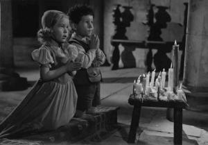 Scena del film "Condottieri" - Regia Luis Trenker - 1937 - Due bambini-attori non identificati pregano inginocchiati davanti a delle candele