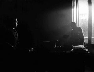 Scena del film "Il Conformista" - Regia Bernardo Bertolucci - 1970 - L'attore Jean-Louis Trintignant, nell'oscurità, osserva un attore non identificato alla scrivania