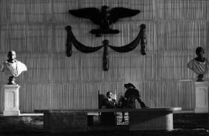 Scena del film "Il Conformista" - Regia Bernardo Bertolucci - 1970 - Un attore non identificato accarezza la gamba ad un'attrice non identificata, seduta sulla scrivania di un enorme salone