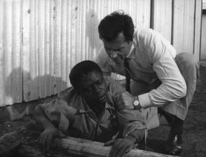 Scena del film "Congo vivo" - Regia Giuseppe Bennati - 1961- L'attore Bachir Touré, ferito, viene aiutato dall'attore Gabriele Ferzetti accovacciato alle sue spalle