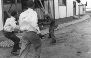 Scena del film "Congo vivo" - Regia Giuseppe Bennati - 1961- Due attori non identificati minacciati da un soldato armato di fucile