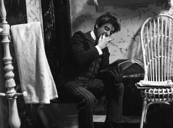 Fotografia del film "Cuore di cane" - Regia Alberto Lattuada 1976 - L'attore Cochi Ponzoni seduto in una stanza da bagno mangia un frutto e legge una rivista.
