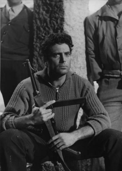 Fotografia del film "Cuori senza frontiere" - Regia Luigi Zampa 1950 - L'attore Raf Vallone seduto con in mano una mitraglia.