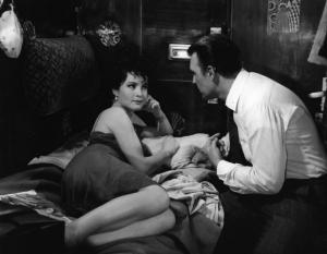 Set del film "Il criminale" - Regia Marcello Baldi- 1962 - L'attrice Yvonne Furneaux stesa su un lettino di uno scompartimento di un treno con accanto 
l'attore Jack Palance.