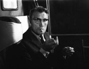 Set del film "Il criminale" - Regia Marcello Baldi- 1962 - Jack Palance seduto in uno scompartimento si accende la sigaretta guardando in camera.