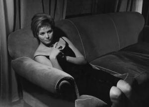 Fotografia del film "I delfini" - Regia Francesco Maselli 1960 - L'attrice Claudia Cardinale seduta su un divano con in mano un bicchiere.