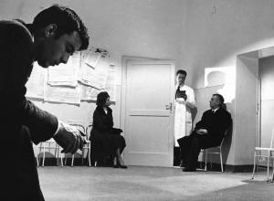Fotografia del film "I delfini" - Regia Francesco Maselli 1960 - L'attore Gérard Blain e altri attori non identificati in una sala d'attesa.