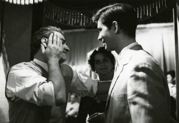 Sul set del film "La diga sul Pacifico" - Regia René Clément, 1957 - René Clement, tiene per un braccio Anthony Perkins mentre con la mano destra si accarezza il viso. Accanto a loro, Alida Valli osserva la scena e sorride.
