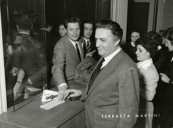 Sul set del film "La dolce vita" - Regia Federico Fellini, 1960 - Federico Fellini, in biglietteria, e Marcello Mastroianni alla presentazione in anteprima alla stampa de "La dolce vita" presso la Terrazza Martini.
