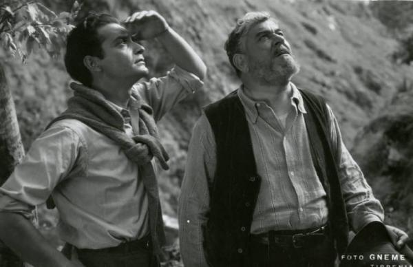 Sul set del film "Don Buonaparte" - Regia Flavio Calzavara, 1941 - Mezza figura di Mino Doro e di un attore non identificato che guardano il cielo. Mino Doro, ha una mano sulla fronte per schermarsi gli occhi dalla luce.