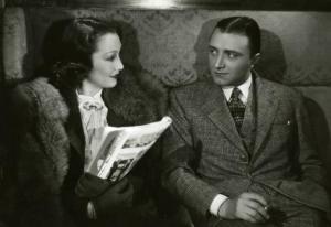 Scena del film "Diamanti" - Regia Corrado D'Errico, 1939 - Mezza figura: Laura Nucci, a sinistra, tiene in mano un giornale mentre parla con Enrico Glori, a destra.
