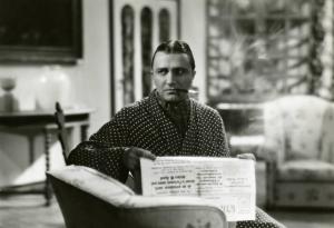 Scena del film "Diamanti" - Regia Corrado D'Errico, 1939 - Mezza figura: Enrico Glori, al centro, seduto, con lo sguardo rivolto a destra, tiene in mano un giornale e in bocca una sigaretta.