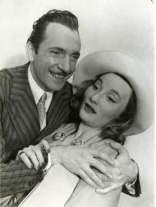 Sul set del film "Divieto di sosta" - Regia Marcello Albani, 1941 - Mezza figura di Nino Crisman mentre abbraccia Silvia Manto circondandole le spalle. L'attrice stringe il polso di lui con una mano.