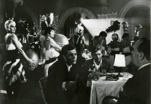 Scena del film "La dolce vita" - Regia Federico Fellini, 1960 - Marcello Mastoianni e Walter Santesso, seduti al tavolo di un night, parlano con Annibale Ninchi. Dietro di loro, Magali Noël apre una fila di ballerine.