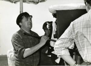 Sul set del film "La dolce vita" - Regia Federico Fellini, 1960 - Mezza figura: Federico Fellini, in piedi, dietro alla macchina da presa.