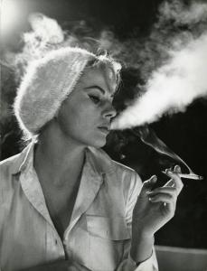 Sul set del film "La dolce vita" - Regia Federico Fellini, 1960 - Mezza figura di profilo di Anita Ekberg che indossa un basco di paillettes e fuma.