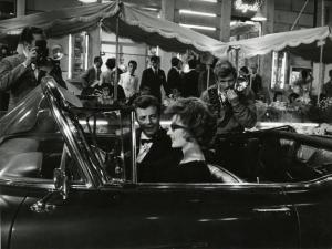 Scena del film "La dolce vita" - Regia Federico Fellini, 1960 - Seduti in una decappottabile, Anouk Aimée, è al posto di guida e Marcello Mastroianni, accanto a lei, la guarda. A sinistra un paparazzo li fotografa, a destra, Walter Santesso.