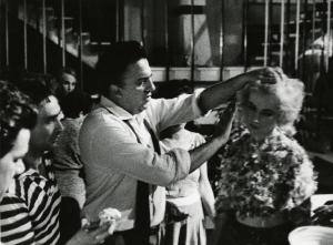 Sul set del film "La dolce vita" - Regia Federico Fellini, 1960 - Federico Fellini acconcia, con le mani, i capelli di Franca Pasutt. Attorno a loro, la troupe.