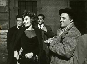 Sul set del film "La dolce vita" - Regia Federico Fellini, 1960 - Da sinistra Marcello Mastroianni, Anouk Aimée, un attore non identificato e Federico Fellini guardano verso qualcuno o qualcosa.