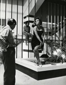 Scena del film "La dolce vita" - Regia Federico Fellini, 1960 - Nadia Gray, in piedi, in sottoveste, si slaccia il reggicalze. A sinistra, in piedi, Mino Doro, la guarda. Sullo sfondo, Sandra Tesi, seduta su un soppalco.