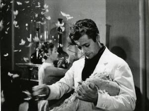 Scena del film "La dolce vita" - Regia Federico Fellini, 1960 - Mezza figura di Marcello Mastroianni mentre spiuma un cuscino. Sullo sfondo, un attrice non identificata.