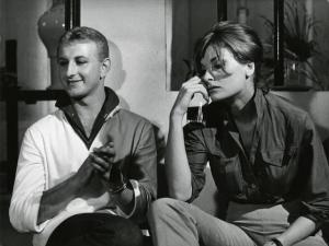 Scena del film "La dolce vita" - Regia Federico Fellini, 1960 - Piano medio di Gioacchino Stajano e Leontine van Strein, seduti. Lui applaude sorridente. Lei, tiene in mano un bicchiere mezzo pieno, e appoggia il gomito sul ginocchio.