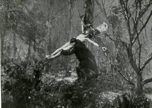 Scena del film "Don Camillo" - Regia Julien Duvivier, 1952 - Totale. In un bosco, sotto una pioggia scrosciante, Fernandel porta a spalla un crocifisso.