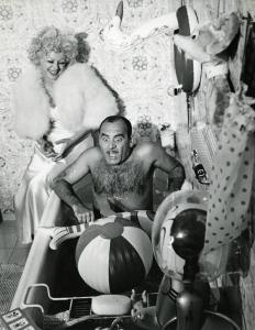 Scena del film "La donna è una cosa meravigliosa" - Regia Mauro Bolognini, 1964 - Vittorio Caprioli, nudo, in una vasca da bagno, con tanti gonfiabili da mare, ha gli occhi e la bocca spalancati. Sandra Milo seduta sul bordo lo guarda e ride.