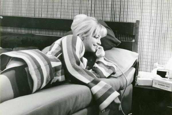 Scena del film "Don Giovanni in Sicilia" - Regia Alberto Lattuada, 1967 - Ewa Aulin, sdraiata su un fianco sul letto, mentre sorride con la testa poggiata su un cuscino e la cornetta del telefono attaccata all'orecchio.