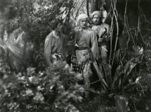 Scena del film "Le due tigri" - Regia Giorgio Candido Simonelli, 1941- Cesare Fantoni, a destra, guarda due attori non identificati, al centro e a sinistra, mentre tiene in mano un fucile.