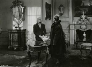 Scena del film "È caduta una donna" - Regia Alfredo Guarini, 1941 - A sinistra, Isa Miranda osserva un'attrice non identificata girata di spalle sull'altro lato del tavolo di un salotto.