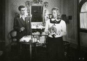 Scena del film "L'ebbrezza del cielo" - Regia Giorgio Ferroni, 1940 - Aldo Fiorelli, a sinistra, dialoga con Silvana Jachino, a destra, mentre tiene le mani giunte al petto e rivolge lo sguardo a sinistra.