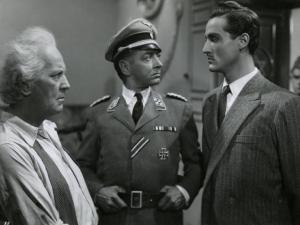 Scena del film "L'ebreo errante" - Regia Goffredo Alessandrini, 1948 - A sinistra di profilo, Pietro Sharoff osserva Vittorio Gassman, a destra, che, a sua volta, osserva un attore non identificato, al centro della scena.