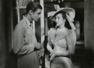 Scena del film "Ecco la felicità!" - Regia Marcel L'Herbier, 1940 - A sinistra, Louis Jourdan con in mano la giacca, e Micheline Presle, a destra, con le mani giunte, si guardano.