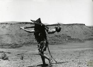 Scena del film "Edipo Re" - Regia Pier Paolo Pasolini, 1967 - In territorio desertico, Francesco Leonetti con abito da indigeno e cappello a tesa larga, trasporta un bambino legato a un bastone.