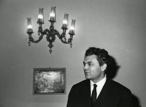 Scena del film "Era notte a Roma" - Regia Roberto Rossellini, 1960 - Mezza figura di Serghej Bondarciuk che osserva alla sua destra con a fianco un quadro e un applique appesi alla parete sullo sfondo.