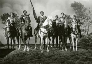 Scena del film "Ettore fieramosca" - Regia Alessandro Blasetti, 1938 - In primo piano, sei attori non identificati schierati a cavallo in abiti di scena. Sul cavallo bianco, il quarto cavaliere da destra tiene in mano un asta con una bandiera.